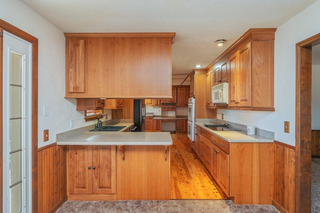 kitchen featuring a peninsula, black appliances, light countertops, and a sink