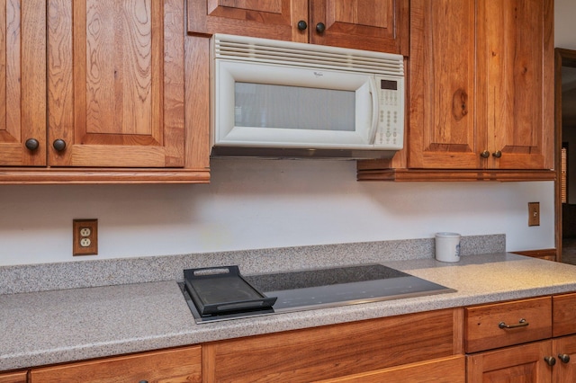 kitchen featuring brown cabinetry, light countertops, and white microwave