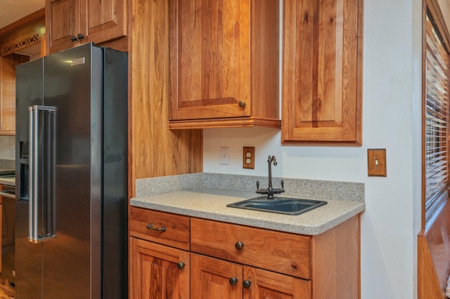 kitchen featuring brown cabinets, light countertops, a sink, and high end refrigerator