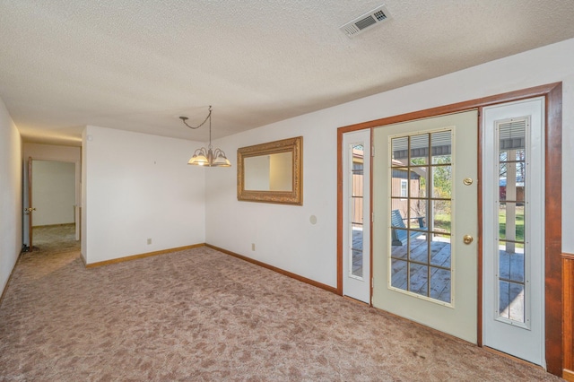 unfurnished room featuring a notable chandelier, a textured ceiling, visible vents, and carpet flooring