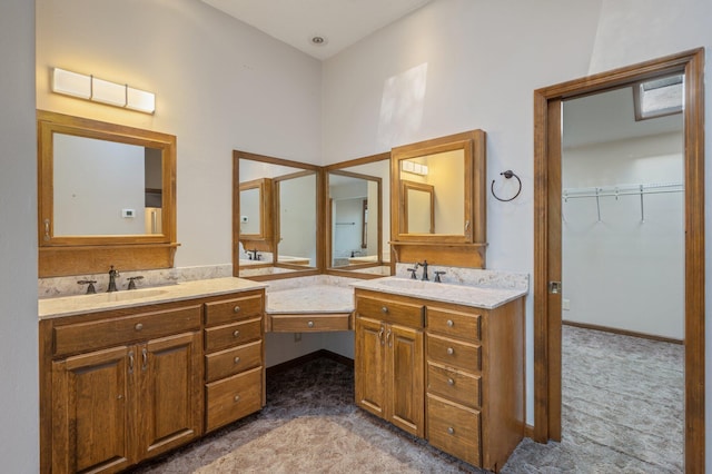 full bathroom featuring two vanities, a sink, and a spacious closet