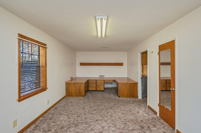 office featuring light carpet, a textured ceiling, baseboards, and built in study area