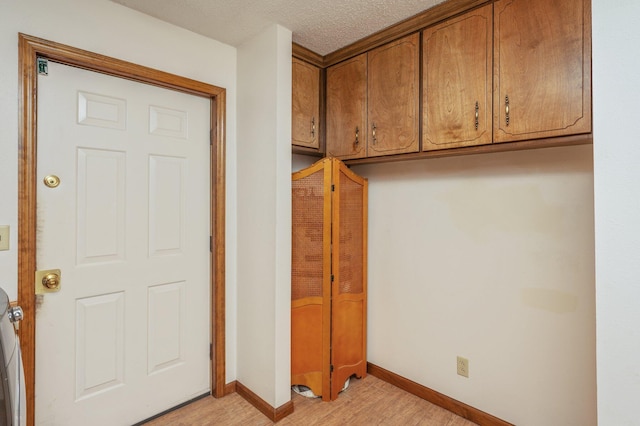 interior space with a textured ceiling, light wood-style flooring, and baseboards