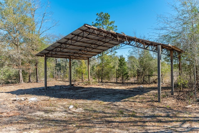 view of parking / parking lot with dirt driveway and a carport