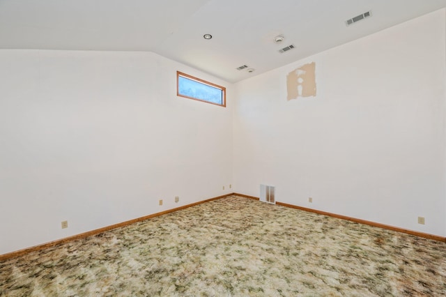 carpeted empty room with vaulted ceiling, visible vents, and baseboards