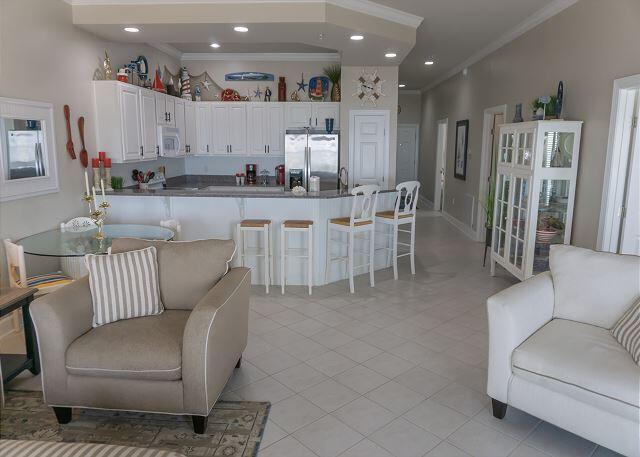 kitchen with white microwave, a kitchen breakfast bar, white cabinets, stainless steel fridge, and crown molding