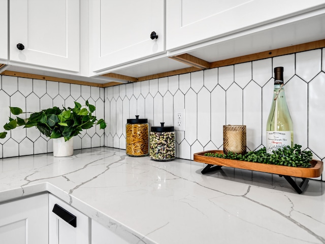 interior details with backsplash, white cabinets, and light stone counters