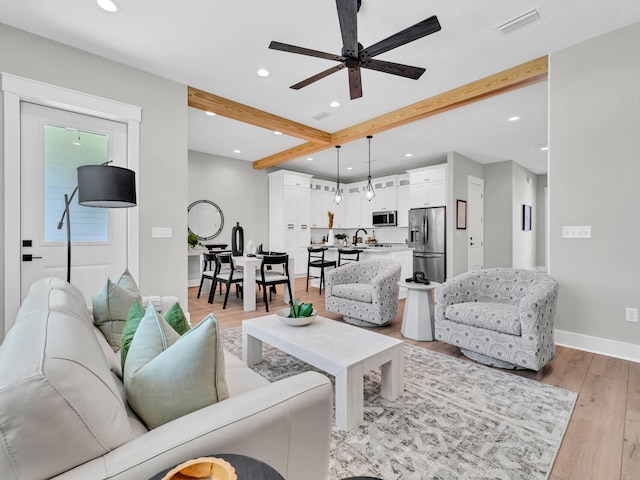 living room with sink, beamed ceiling, ceiling fan, and light hardwood / wood-style flooring