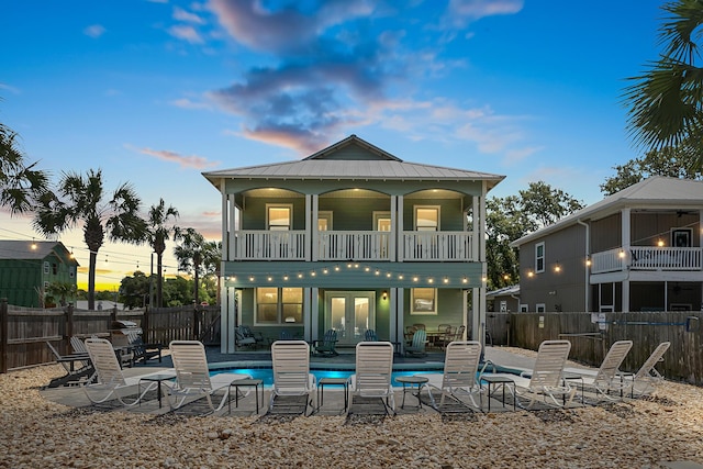 rear view of house with a fenced in pool, a fenced backyard, and a balcony