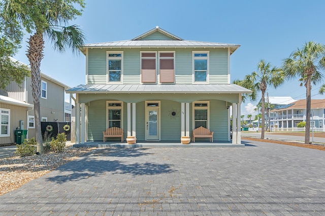 view of front of home featuring a standing seam roof, metal roof, fence, and a porch