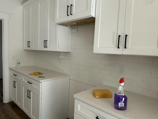 kitchen with white cabinetry, light stone counters, and tasteful backsplash