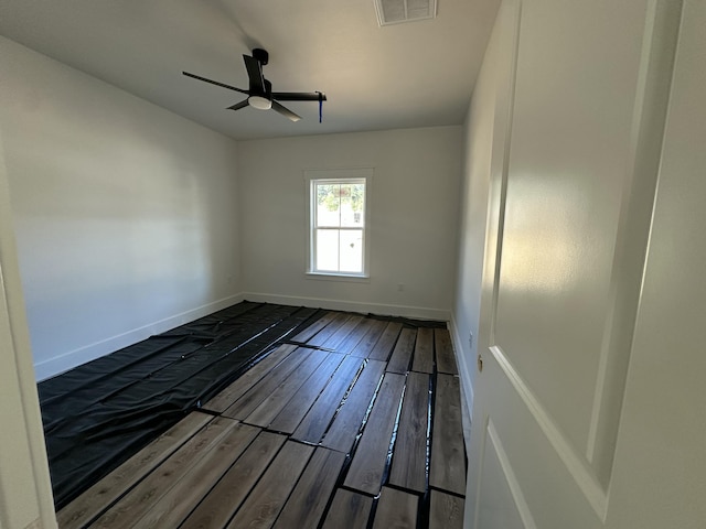 unfurnished room featuring hardwood / wood-style floors, baseboards, visible vents, and a ceiling fan