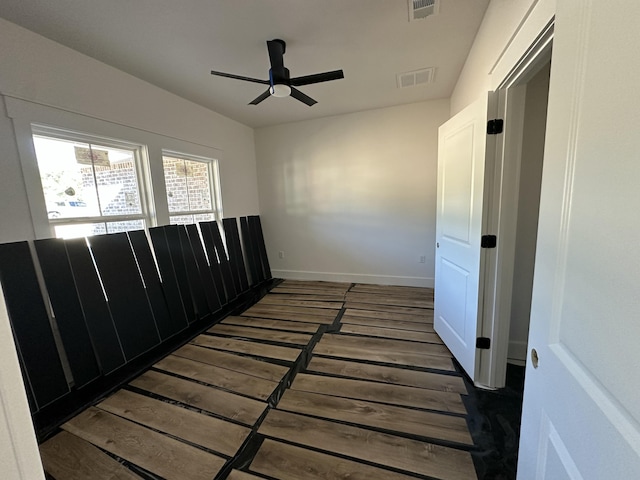 spare room featuring visible vents, baseboards, wood finished floors, and a ceiling fan