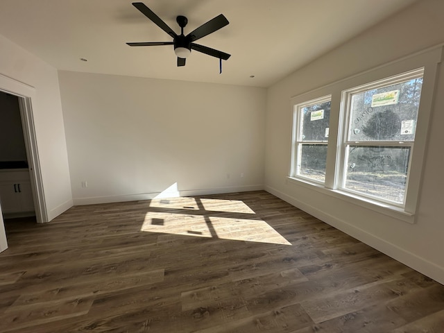 unfurnished room with dark wood-style floors, ceiling fan, and baseboards