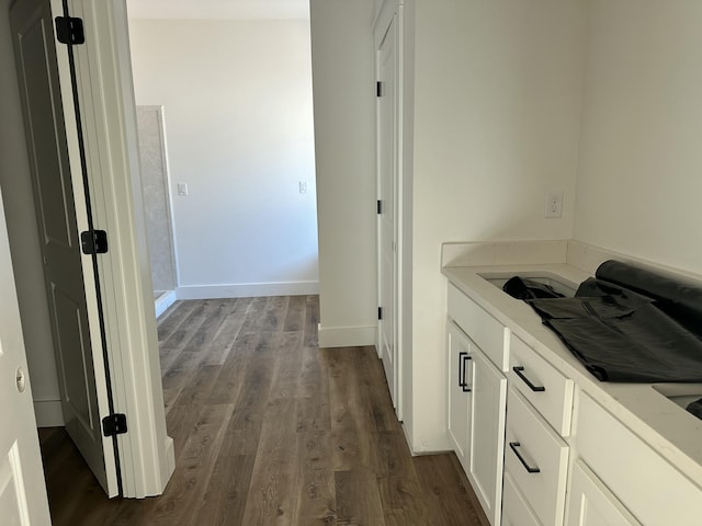 corridor with dark wood-type flooring and baseboards