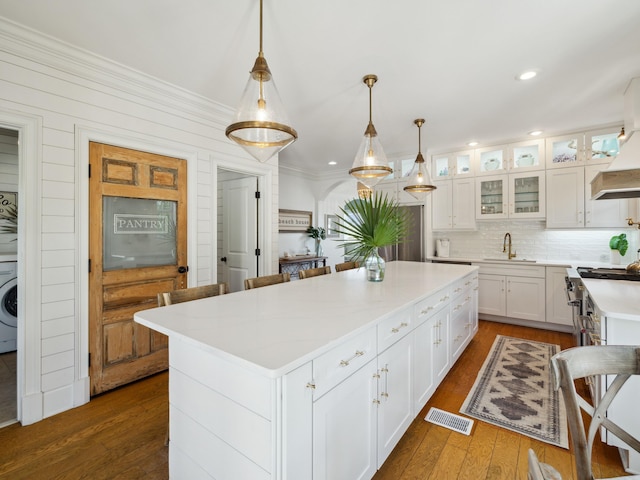 24 High Tide Way, Inlet Beach, FL 32461 - kitchen with a sink, washer / clothes dryer, dark wood finished floors, a center island, and white cabinets