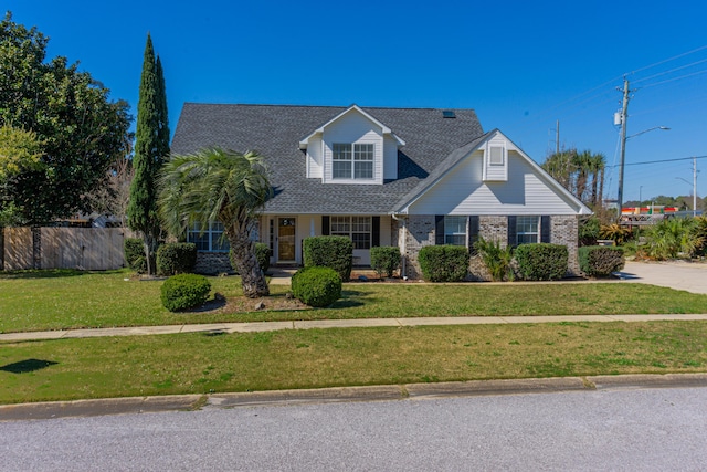 traditional home with a front yard, brick siding, and fence