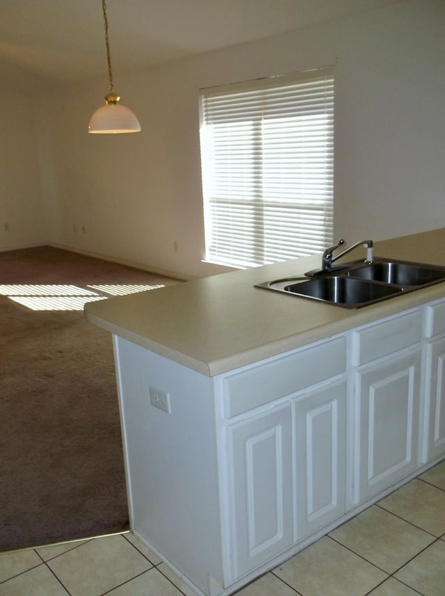 kitchen featuring white cabinets, sink, light tile patterned flooring, and decorative light fixtures