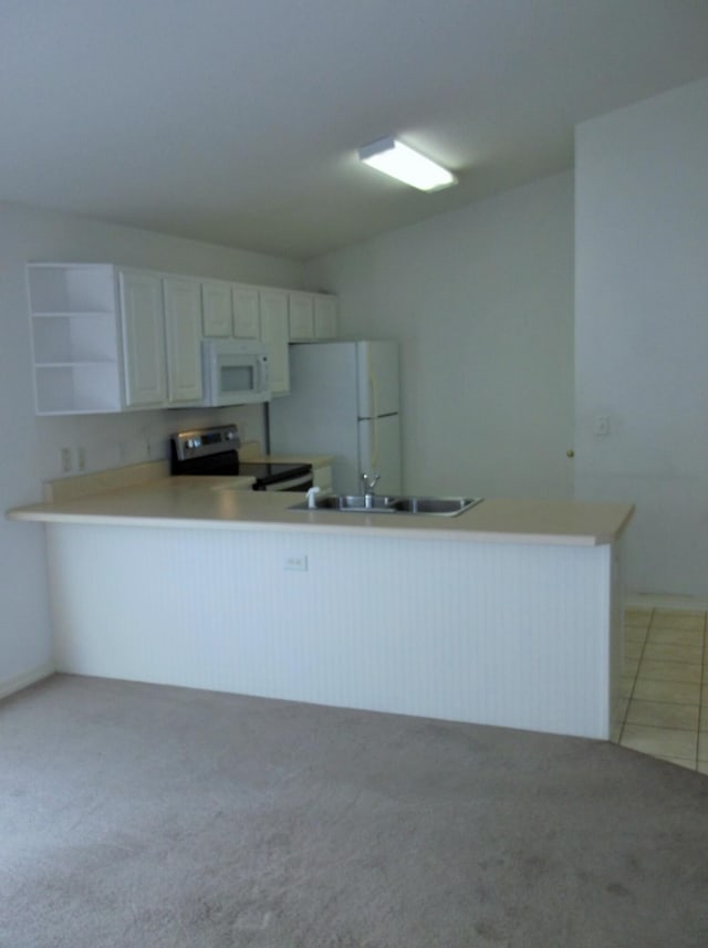 kitchen with carpet, kitchen peninsula, white appliances, and white cabinets