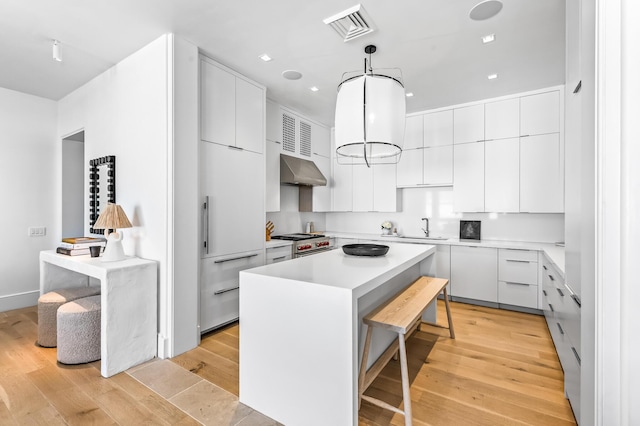 290 Sea Garden St Unit 402, Alys Beach, FL 32461 - kitchen with a breakfast bar area, stainless steel stove, white cabinets, decorative light fixtures, and a center island
