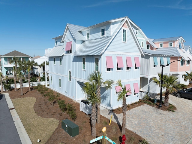 view of front facade featuring decorative driveway, a residential view, a standing seam roof, and metal roof