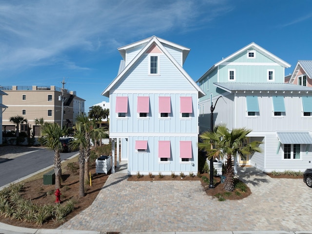 coastal home with metal roof, central AC unit, and board and batten siding