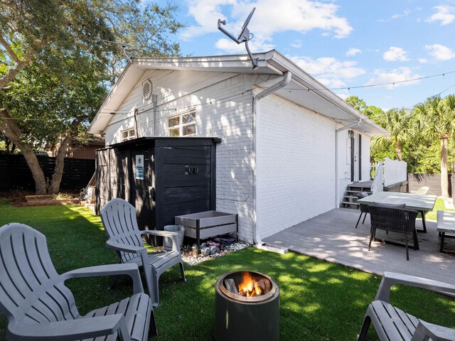 38 Barracuda St, Santa Rosa Beach, FL 32459 - back of property featuring fence, a yard, an outdoor fire pit, brick siding, and a deck