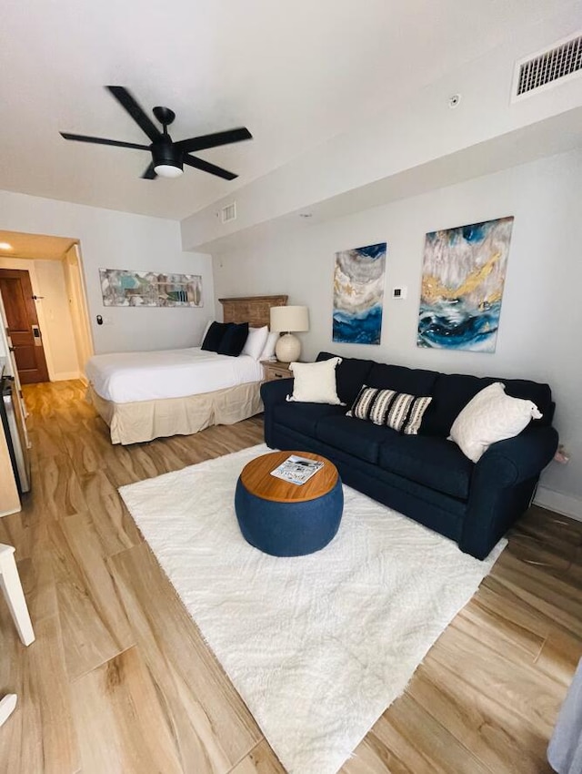 bedroom with light wood finished floors, baseboards, visible vents, and a ceiling fan