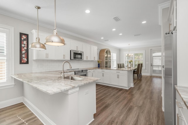 105 Oyster Blvd, Freeport, FL 32439 - kitchen with a peninsula, white cabinets, stainless steel appliances, and decorative light fixtures