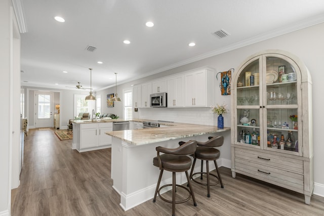 105 Oyster Blvd, Freeport, FL 32439 - kitchen featuring a peninsula, stainless steel appliances, white cabinetry, a kitchen bar, and pendant lighting