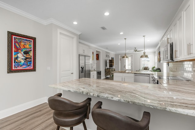 105 Oyster Blvd, Freeport, FL 32439 - kitchen with decorative light fixtures, stainless steel appliances, white cabinets, a peninsula, and a kitchen breakfast bar