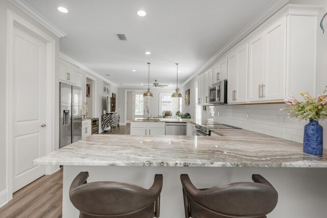 105 Oyster Blvd, Freeport, FL 32439 - kitchen featuring a breakfast bar, hanging light fixtures, appliances with stainless steel finishes, white cabinets, and a peninsula