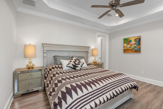 105 Oyster Blvd, Freeport, FL 32439 - bedroom with a tray ceiling, crown molding, visible vents, dark wood-type flooring, and baseboards