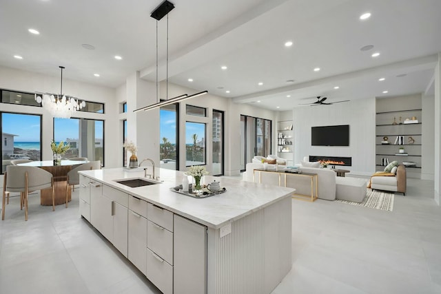 kitchen featuring white cabinets, modern cabinets, a kitchen island with sink, light countertops, and pendant lighting