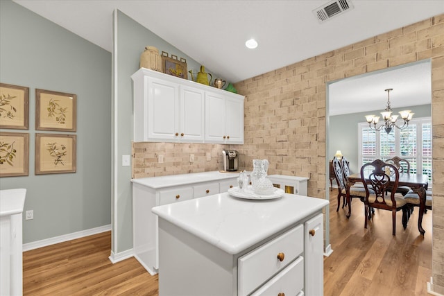 kitchen with hanging light fixtures, a center island, white cabinetry, and light wood-type flooring