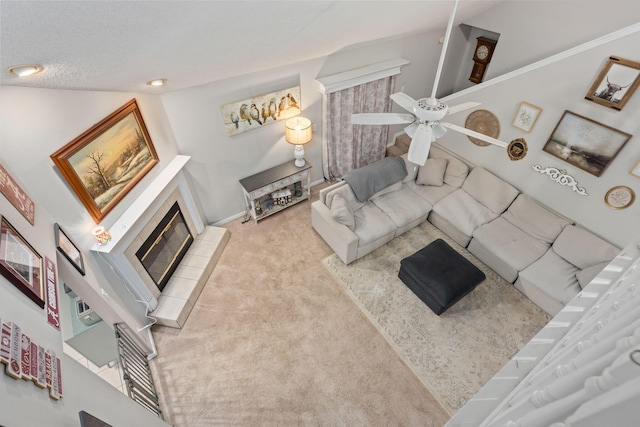 living room with light carpet, a textured ceiling, a fireplace, and a ceiling fan