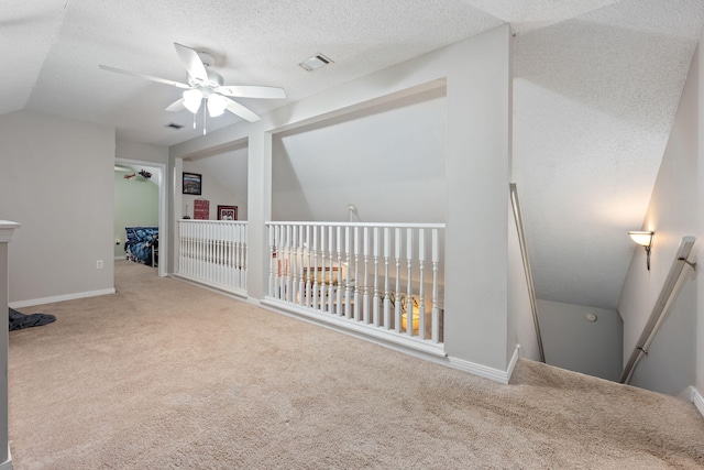 bonus room featuring a textured ceiling, carpet floors, visible vents, a ceiling fan, and vaulted ceiling