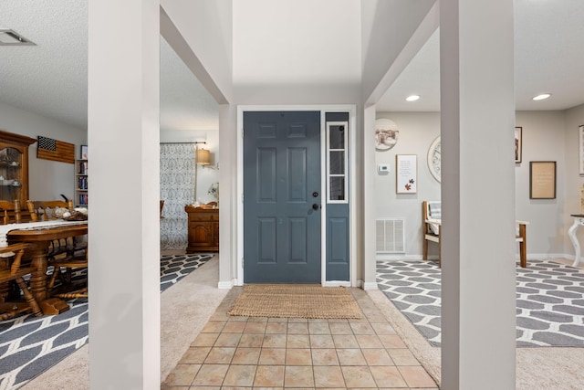 foyer featuring light carpet, baseboards, visible vents, and recessed lighting