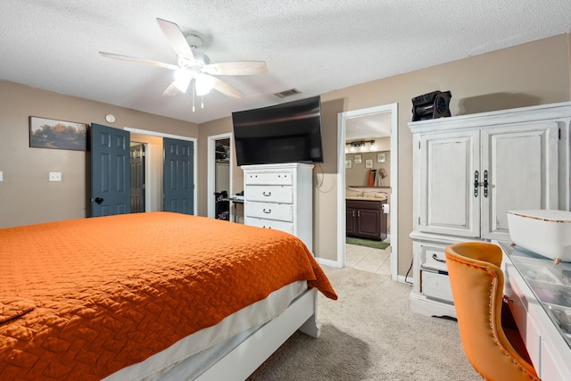 bedroom featuring a textured ceiling, connected bathroom, visible vents, and light colored carpet