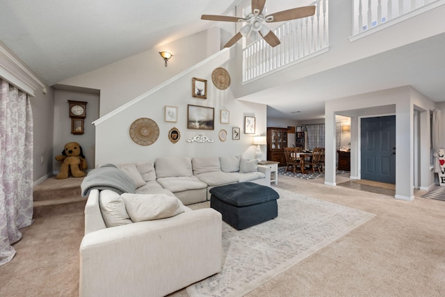 living room featuring high vaulted ceiling, ceiling fan, baseboards, and light colored carpet