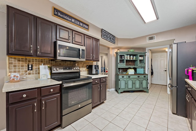 kitchen featuring dark brown cabinets, stainless steel appliances, and light countertops