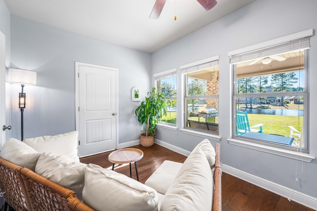 living area with wood finished floors, a ceiling fan, and baseboards