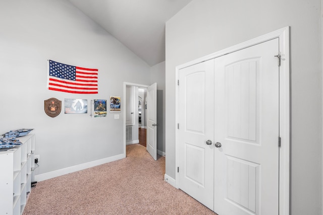 hallway with light carpet, lofted ceiling, and baseboards