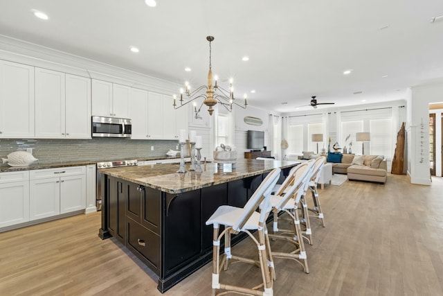125 Gulfview Cir, Santa Rosa Beach, FL 32459 - kitchen featuring an island with sink, light stone countertops, appliances with stainless steel finishes, white cabinets, and pendant lighting