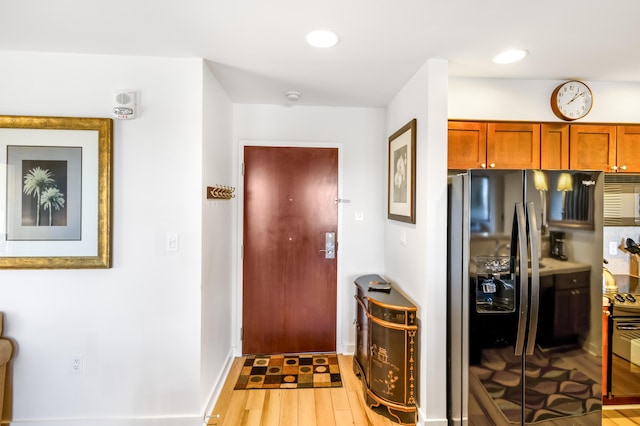 kitchen with light wood-style flooring, brown cabinetry, black fridge, and recessed lighting