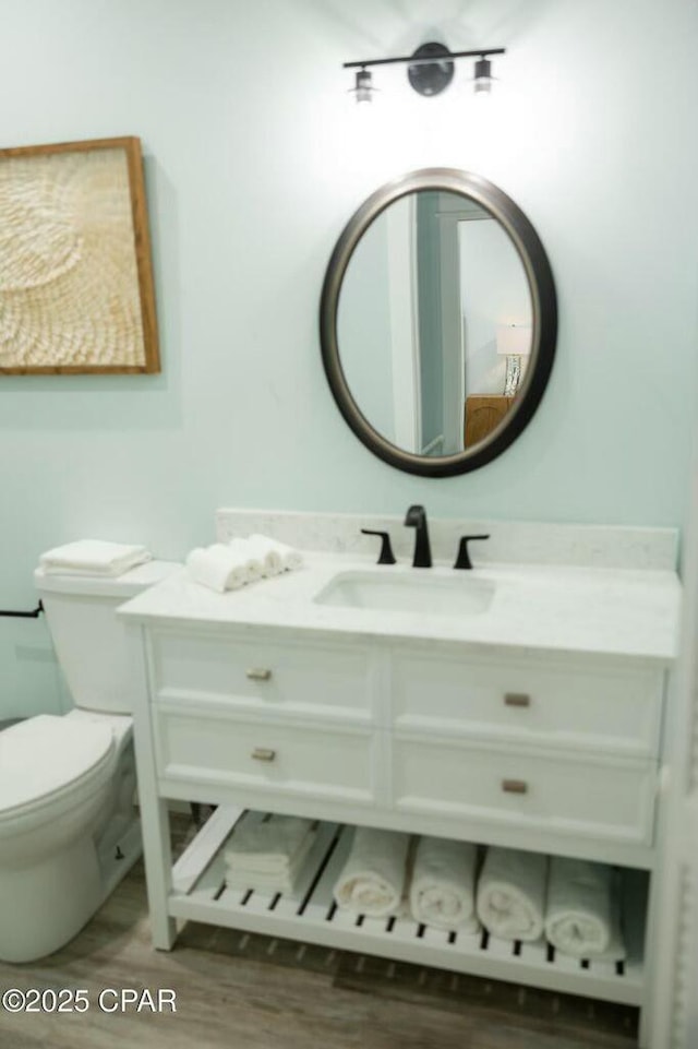 bathroom with toilet, wood-type flooring, and vanity