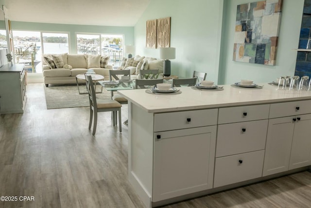 kitchen with white cabinets, light hardwood / wood-style floors, lofted ceiling, and a center island