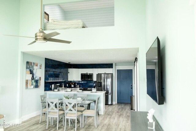 interior space featuring kitchen peninsula, stainless steel appliances, tasteful backsplash, ceiling fan, and white cabinets