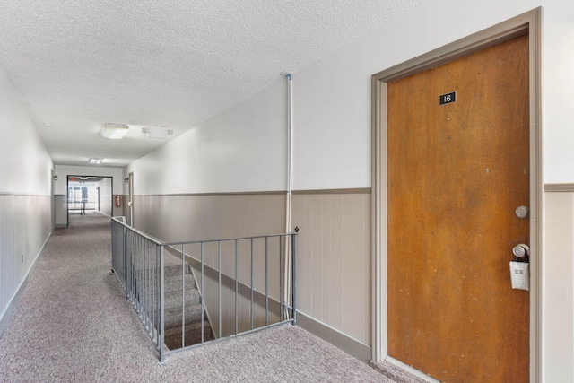 corridor with carpet floors and a textured ceiling