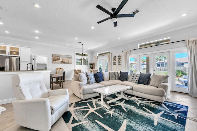 living area with a textured ceiling, french doors, ornamental molding, and visible vents